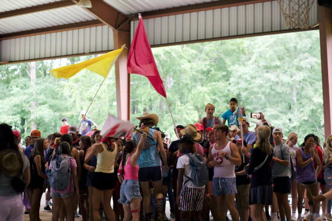 Children gathered under colourful flags at a summer camp