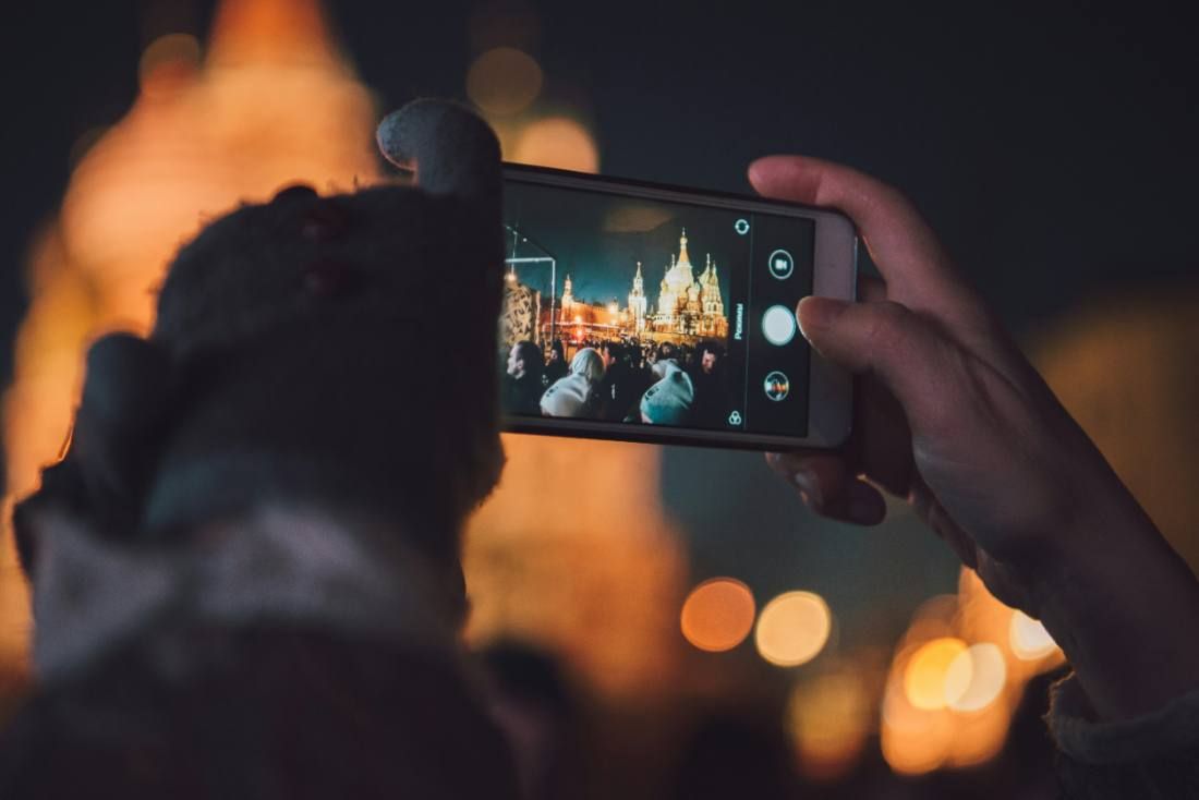 A phone held up at night showing a photo of the evening